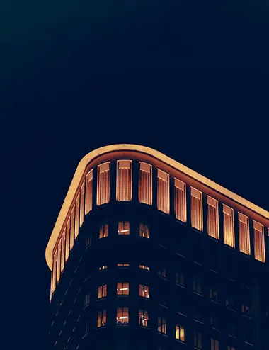 The top windows of a curved building, lit up at night